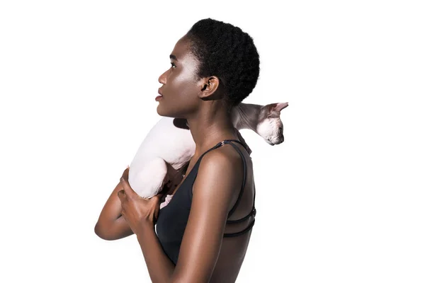Vista lateral de joven afroamericana mujer en traje de baño sosteniendo gato y mirando hacia otro lado aislado en blanco — Stock Photo