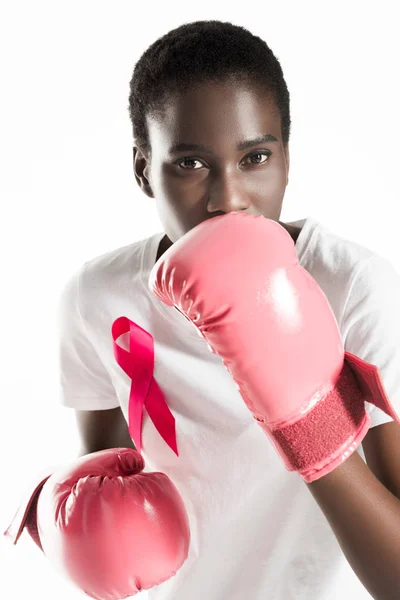 Young woman with ribbon on t-shirt boxing and looking at camera isolated on white, breast cancer concept — Stock Photo