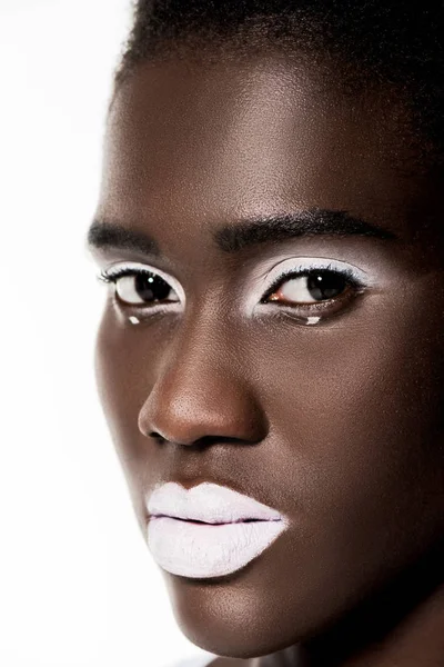 Primer plano retrato de hermosa chica afroamericana pensativa con labios blancos mirando a la cámara aislada en blanco - foto de stock