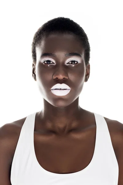 Retrato de atractiva chica afroamericana tierna con maquillaje blanco mirando a la cámara aislada en blanco - foto de stock