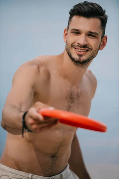 Close-up view of smiling young man holding flying disc and looking at camera — Stock Photo