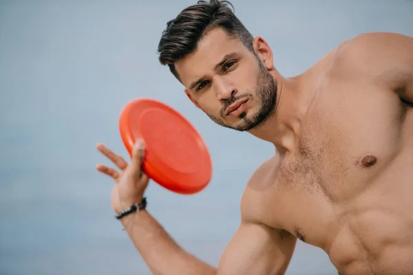 Handsome young man holding flying disk and looking at camera — Stock Photo