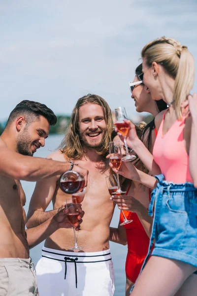 Happy young male and female friends holding glases and pouring wine on beach — Stock Photo