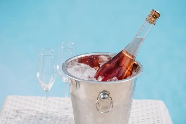 Botella de champán en cubo con hielo y dos vasos vacíos junto a la piscina - foto de stock