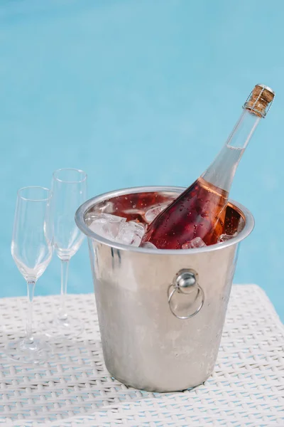 Vista ravvicinata della bottiglia di champagne in secchio con ghiaccio e due bicchieri vuoti a bordo piscina — Foto stock