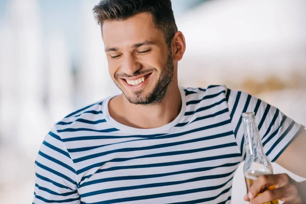 Bonito sorrindo jovem segurando garrafa de vidro com cerveja — Fotografia de Stock