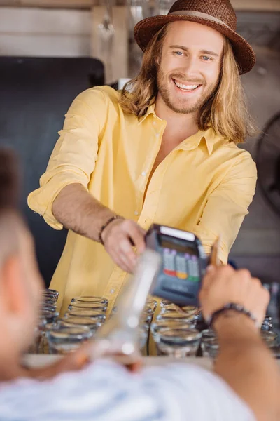 Selective focus of young man paying with credit card at beach bar — Stock Photo
