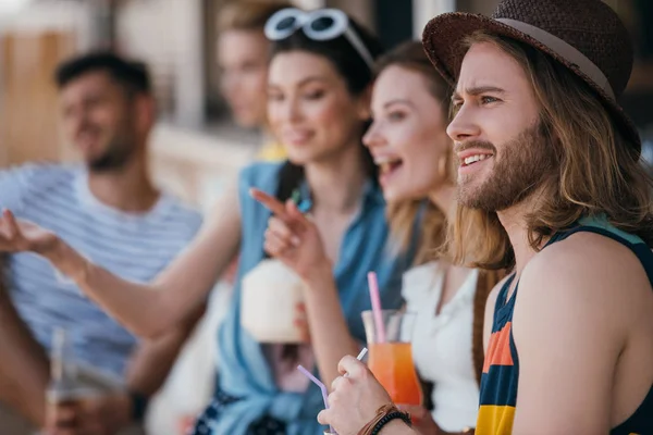 Щасливі молоді друзі п'ють коктейлі і дивляться на пляжний бар — стокове фото