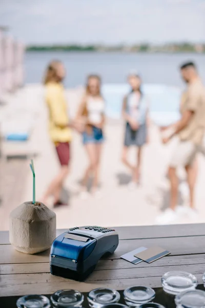 Vista de cerca de cócteles, tarjetas de crédito y terminal de pago en el mostrador de bar de madera en el bar de la playa - foto de stock