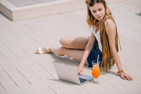 Hermosa mujer joven usando el ordenador portátil y mirando al aire libre - foto de stock