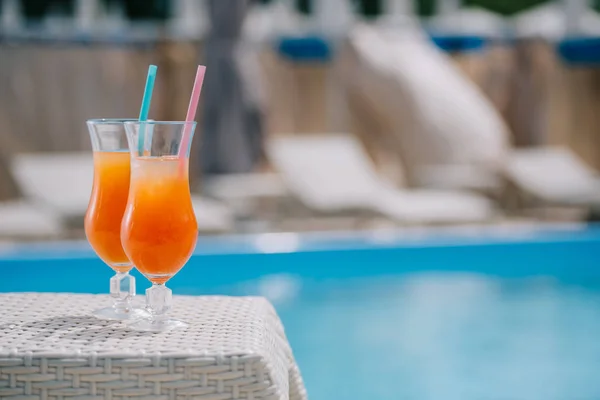 Vista de cerca de vasos con cócteles de verano y pajitas para beber en la piscina - foto de stock