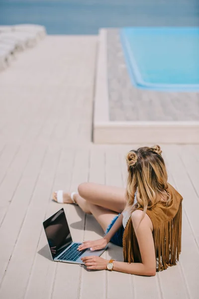 Visão de alto ângulo da menina usando laptop com tela preta na beira da piscina — Fotografia de Stock