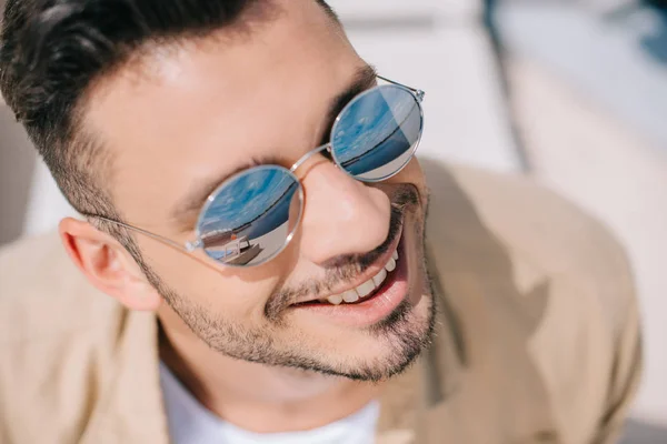 Close-up portrait of handsome young man in sunglasses smiling outdoors — Stock Photo
