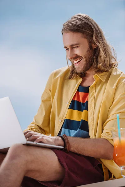 Smiling young man using laptop at summer day — Stock Photo