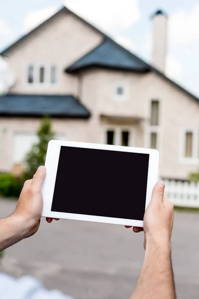 Cropped shot of man holding digital tablet with blank screen in front of cottage — Stock Photo