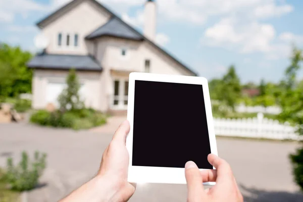 Cropped image of man holding digital tablet with blank screen in front of cottage — Stock Photo