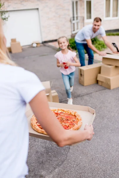 Cropped image of woman holding pizza and daughter with cup of cola running to her — Stock Photo