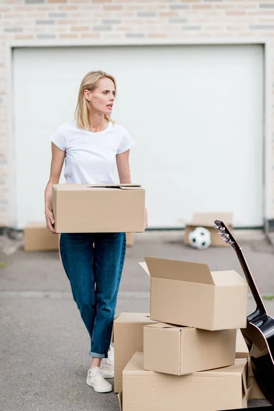 Femme attrayante avec boîte en carton déménageant dans une nouvelle maison — Photo de stock