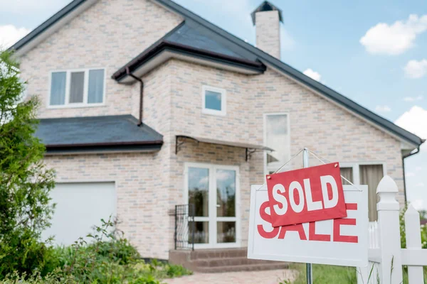 Close up view of sold sign on wooden placard with sale sign in front of modern cottage — Stock Photo