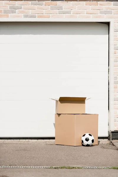 Vista de cerca de las cajas, pelota de fútbol en frente de la puerta del garaje - foto de stock