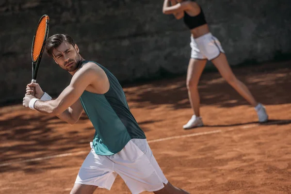 Jeune couple athlétique jouant au tennis en équipe — Photo de stock