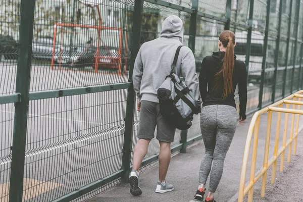 Rear view of sportive couple walking to sports ground — Stock Photo