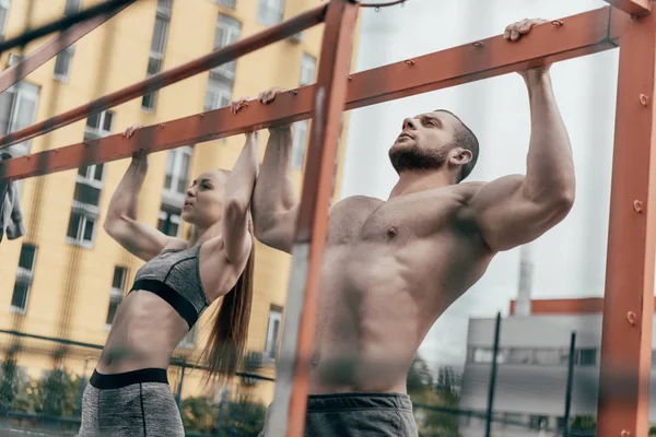 Спортсмен и спортсменка подъезжают к горизонтальной полосе вместе — стоковое фото