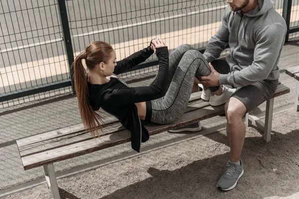 Boyfriend holding girlfriends legs and helping doing sit ups — Stock Photo