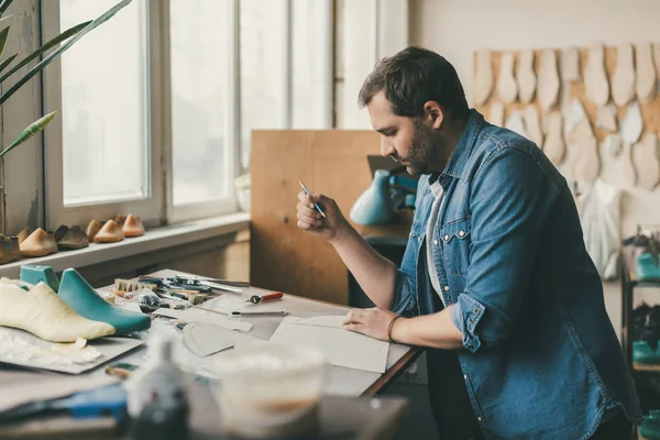 Concentrated young shoemaker at workplace in cobbler's shop — Stock Photo