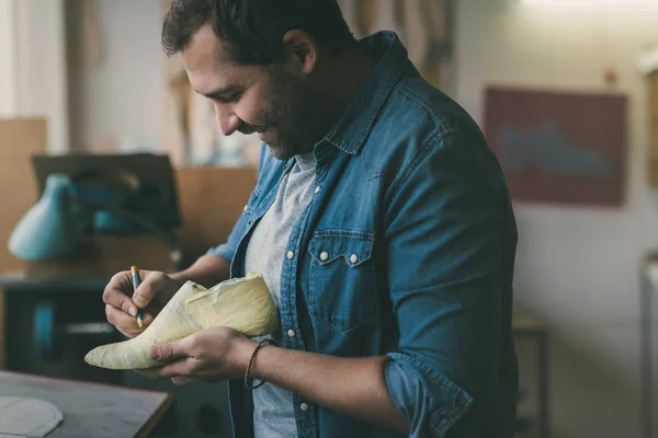 Smiling young shoemaker working with foot sample — Stock Photo