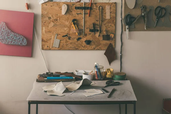 Table with leather samples and various tools with scissors at shoemaker workshop — Stock Photo