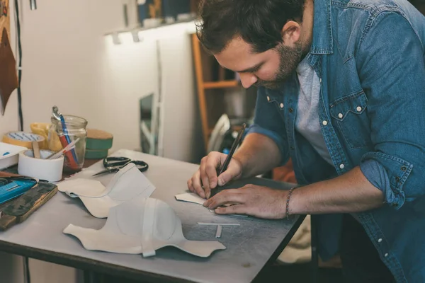 Young shoemaker tracing leather for shoes at workplace — Stock Photo