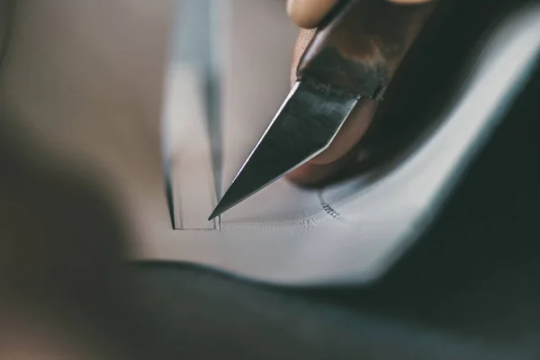 Close-up partial view of shoemaker cutting sole outline with knife — Stock Photo