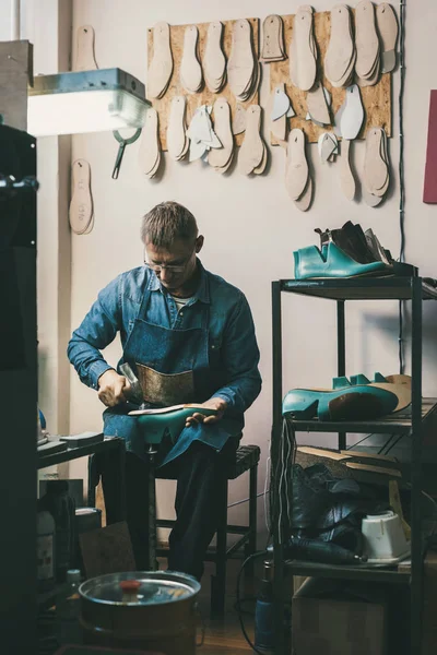 Zapatero maduro trabajando con piezas de calzado en el taller - foto de stock