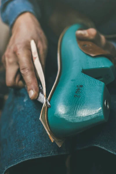 Cropped shot of shoemaker cutting material with knife to size of foot sample — Stock Photo