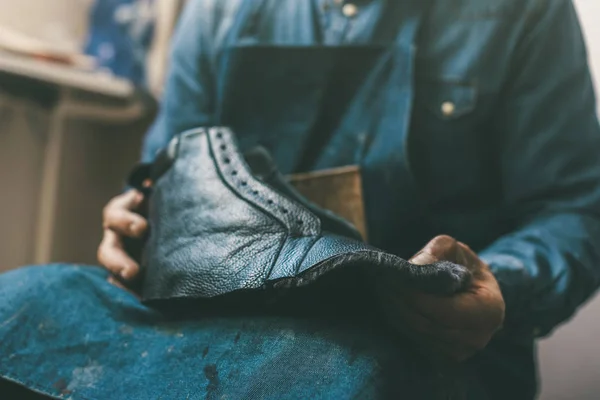 Tiro recortado de zapatero sosteniendo zapato de cuero inacabado en el taller - foto de stock