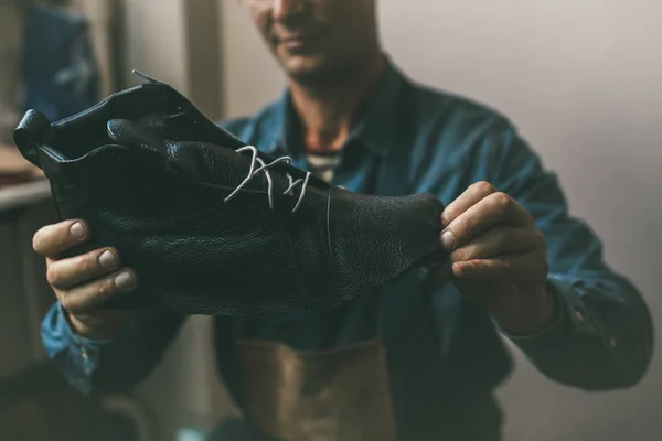 Close-up shot of shoemaker looking at unfinished leather boot — Stock Photo