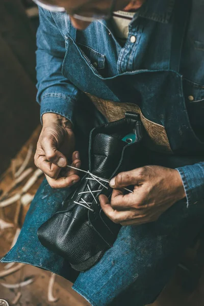 Schuhmacher schnürt unfertige Lederstiefel — Stockfoto