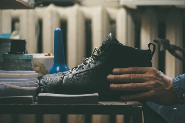 Close-up partial view of shoemaker holding leather shoe at workshop — Stock Photo