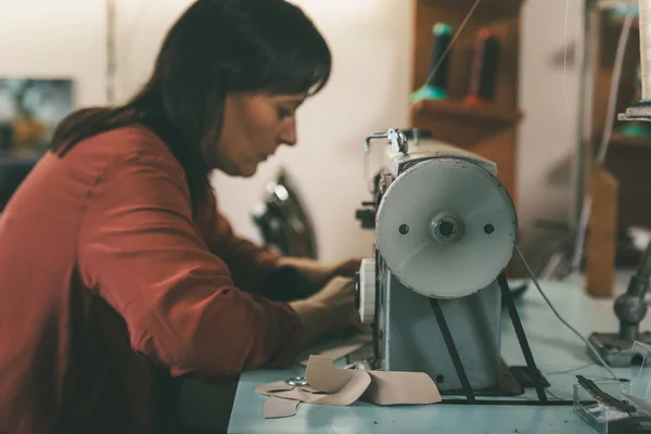 Side view of seamstress working with sewing machine and leather at shoemaker workshop — Stock Photo