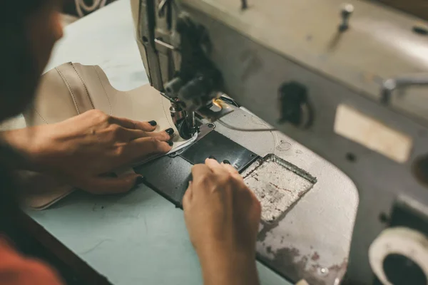 Close-up partial view of seamstress working with sewing machine and leather at shoemaker workshop — Stock Photo