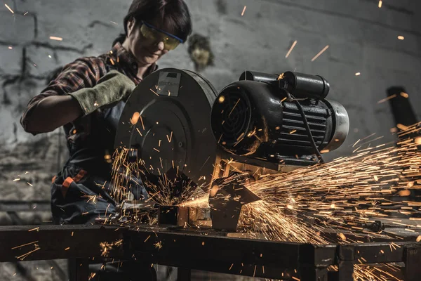 Female welder in protective googles using welding torch in workshop — Stock Photo