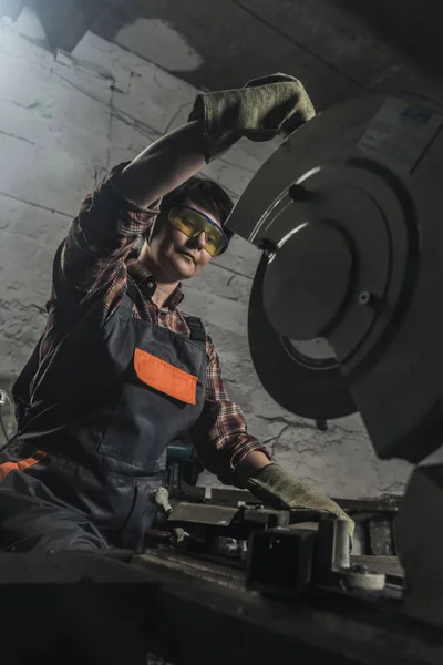 Soldador femenino en googles protectores usando linterna de soldadura en taller - foto de stock