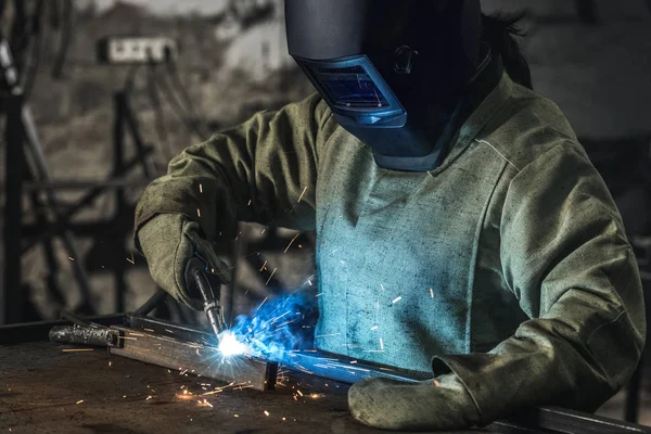 Trabalhador manual em capacete de proteção com tocha de soldagem trabalhando na oficina — Fotografia de Stock