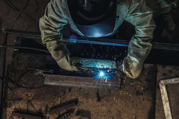 Overhead view of welder in protective work wear holding welding torch in workshop — Stock Photo