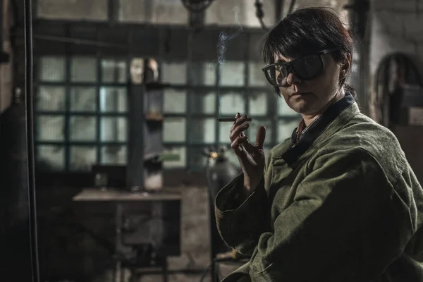 Portrait of female welder looking at camera while smoking cigarette during break — Stock Photo