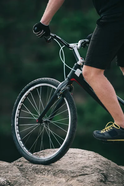 Cropped shot of trial biker balancing on rock outdoors — Stock Photo