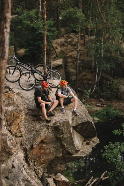 Vista ad alto angolo di felici giovani motociclisti di prova che si rilassano sulla scogliera rocciosa dopo la corsa — Foto stock