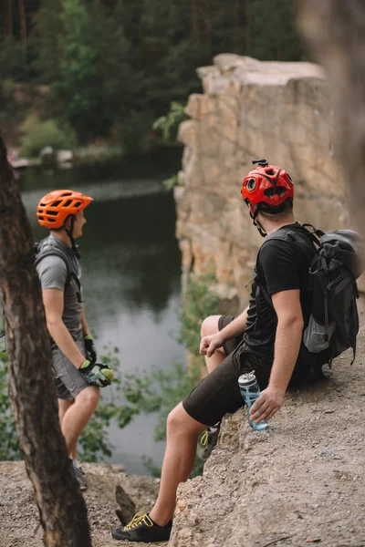 Giovani turisti in caschi relax sulla scogliera rocciosa dopo la corsa — Foto stock