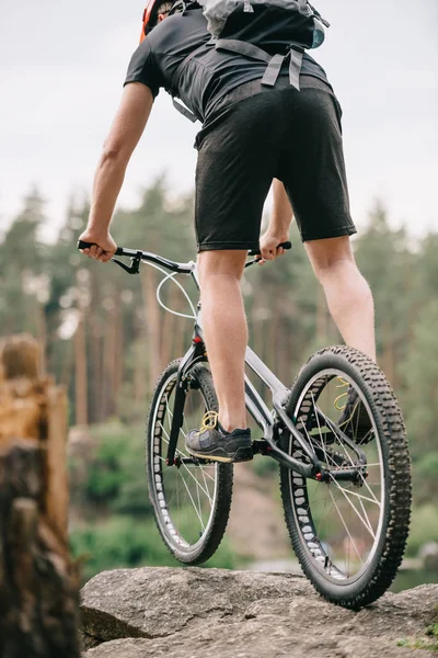 Rear view of trial biker balancing on cliff outdoors — Stock Photo